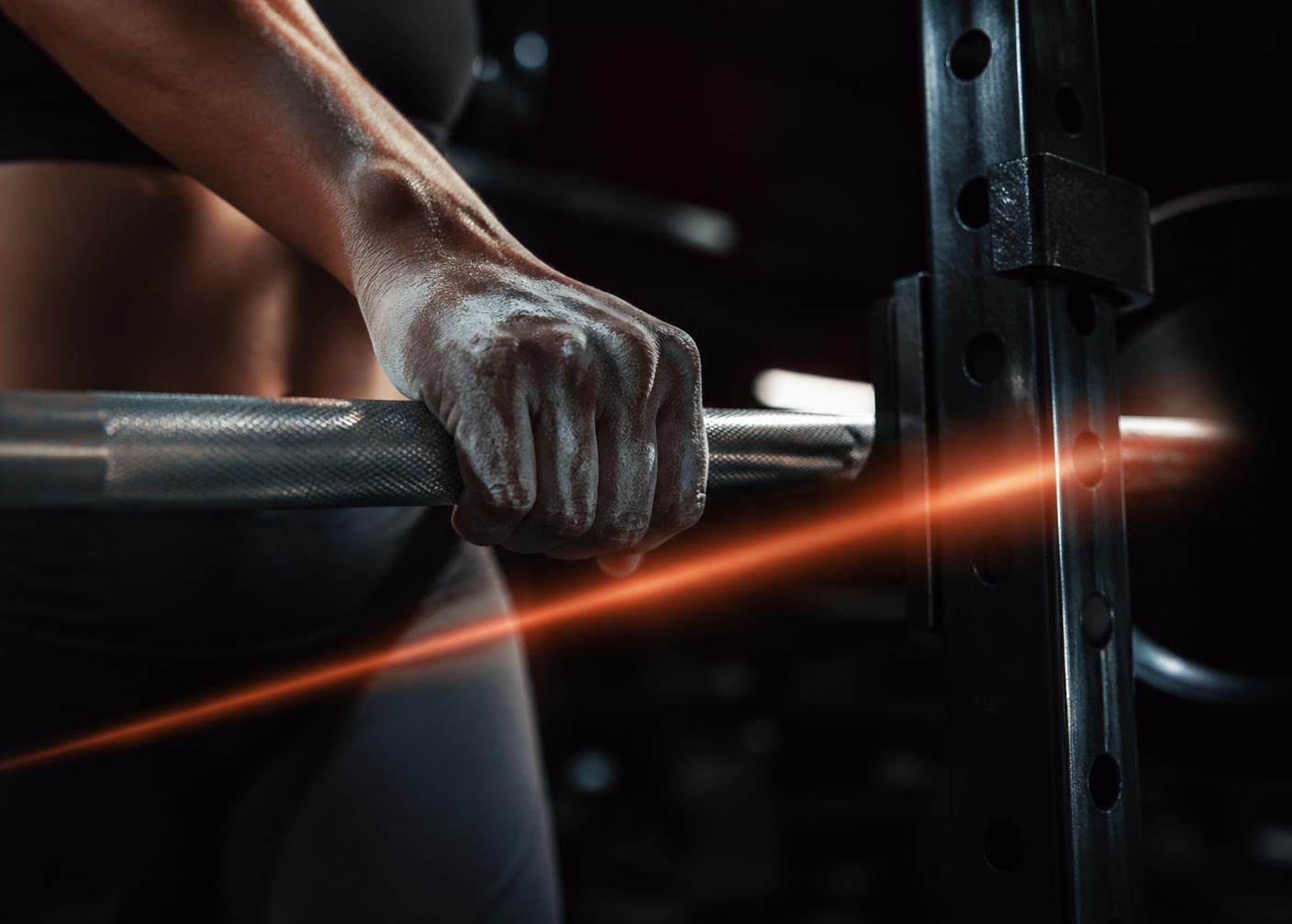 Chalked hands gripping a barbell in a rack